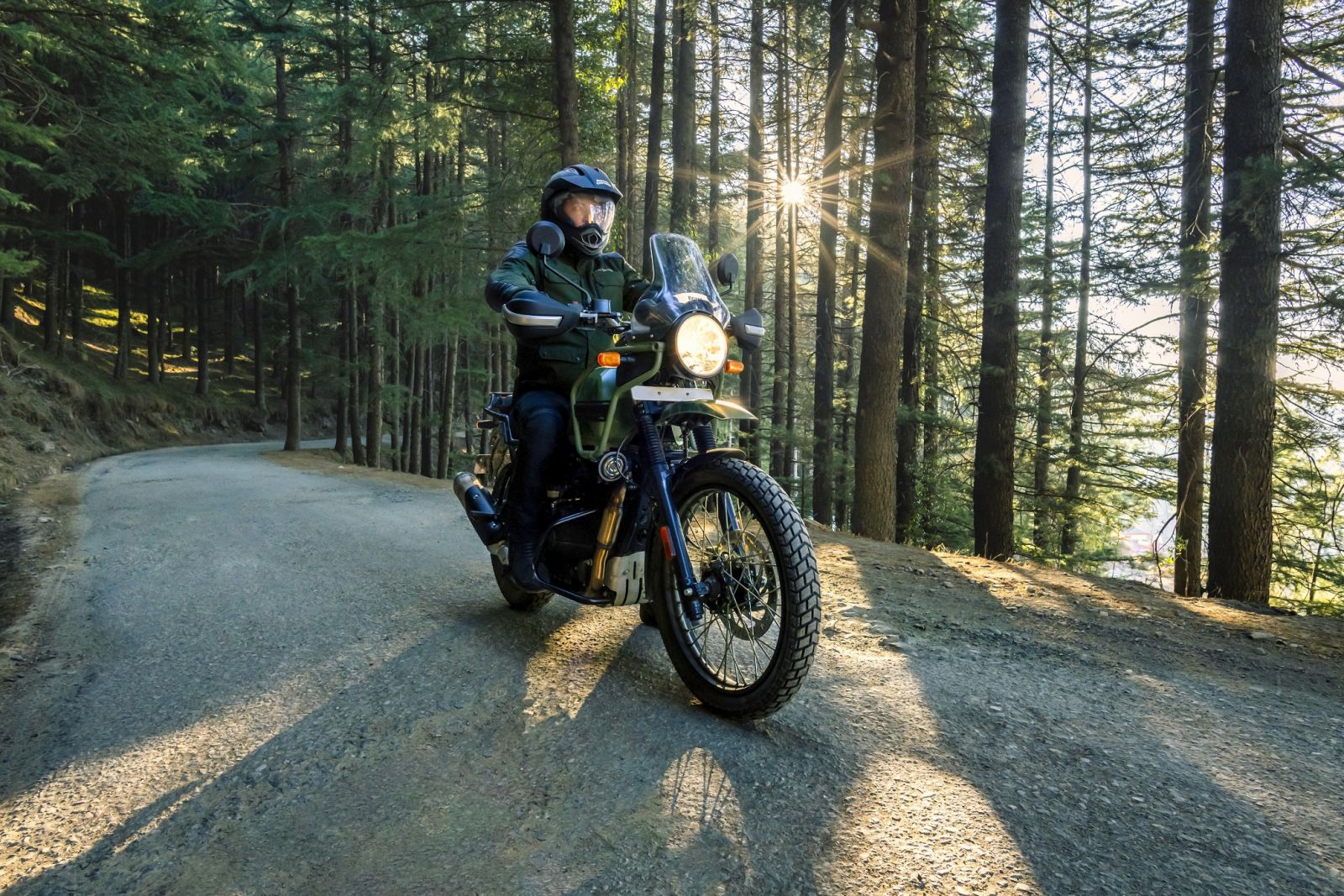 A person riding a motorcycle on a road in the woodsDescription automatically generated with medium confidence